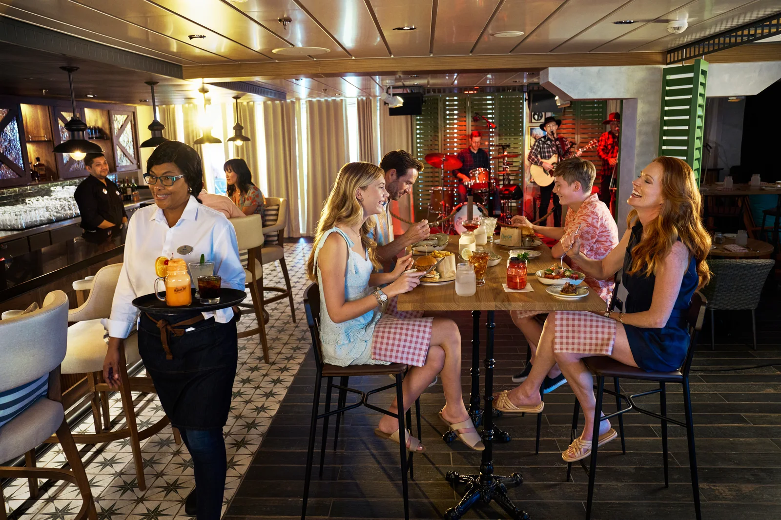Guests dining and enjoying live country music at the Mason Jar bar on Icon of the Seas
